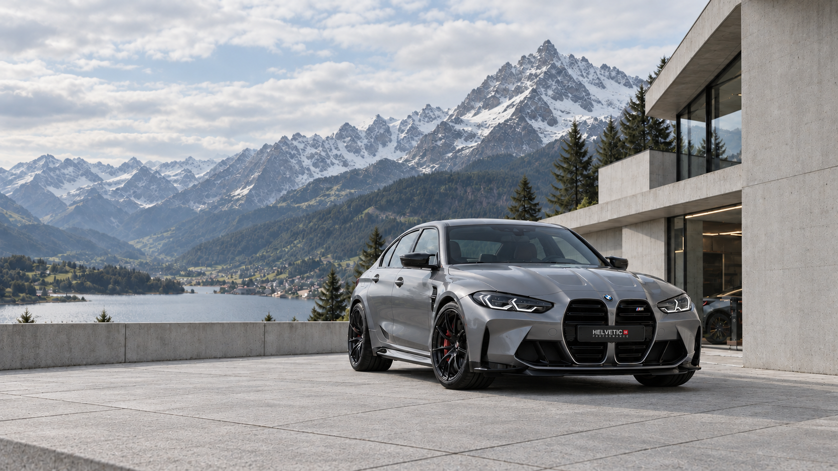 Silberner BMW M3 G80 vor moderner Schweizer Architektur mit Blick auf einen Alpensee.